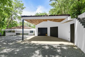 Une maison moderne dotée d’un patio couvert, d’un garage et d’un escalier menant à l’étage supérieur.