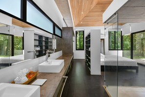 Une salle de bain moderne avec un grand miroir, un lavabo blanc et un espace douche.