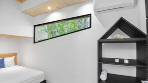 A bedroom with a bed, a window with a view of greenery, a black shelf unit, and a white wall. - Family Home with Private Pool – 5 Min drive to the Beach (Tamarindo)