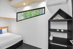 Ein Schlafzimmer mit einem Bett, einem Fenster mit Blick auf Grünflächen, einer schwarzen Regaleinheit und einer weißen Wand.