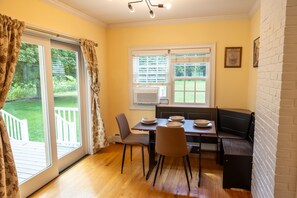 A dining area with a table set for four, a bench, and a view of the outdoors.