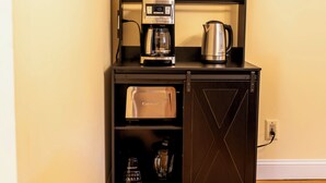 Uma kitchenette compacta com cafeteira, chaleira e liquidificador.