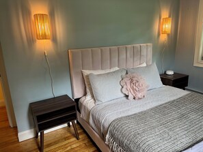 A bedroom with a bed, two bedside tables, and wall-mounted lamps.