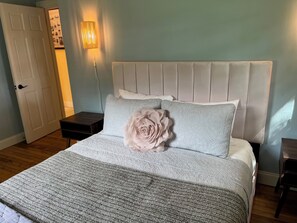 A bedroom with a bed, a nightstand, a wall-mounted lamp, and a door. - Beautiful, Charming and Private house close to EVERYTHING. A/C and Fast Wifi (Orford)