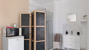 A modern bathroom with a shower, a vanity with a mirror, and a refrigerator.