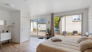 A bedroom with a bed, a desk, and a bathroom.