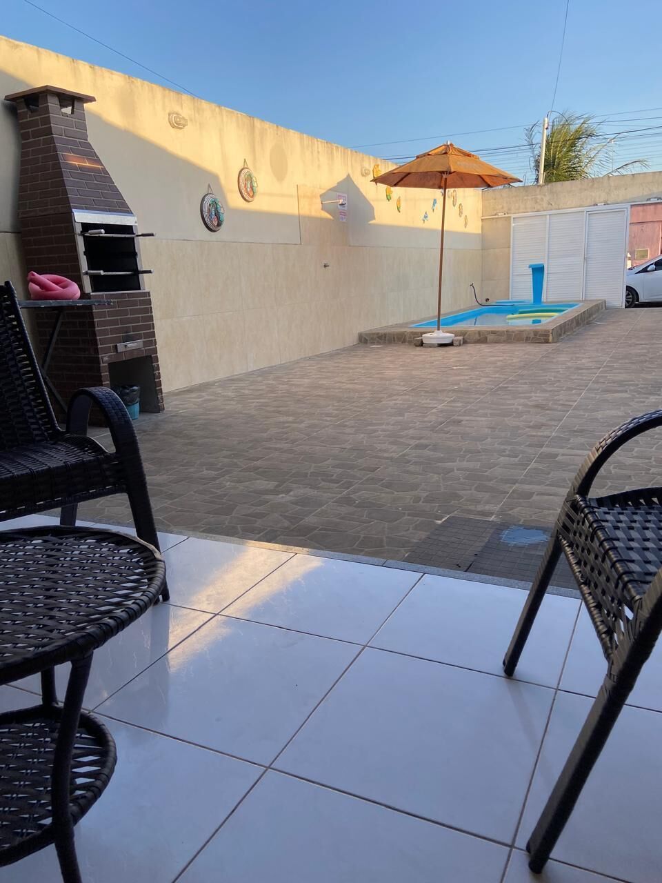 A patio area with a brick wall, a barbecue grill, a small pool, and outdoor furniture.