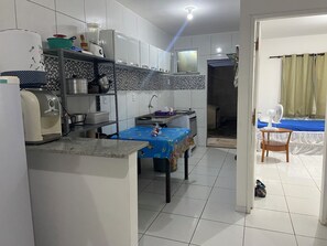 A compact kitchen with a dining area, a small table, and a bed in the adjacent room.