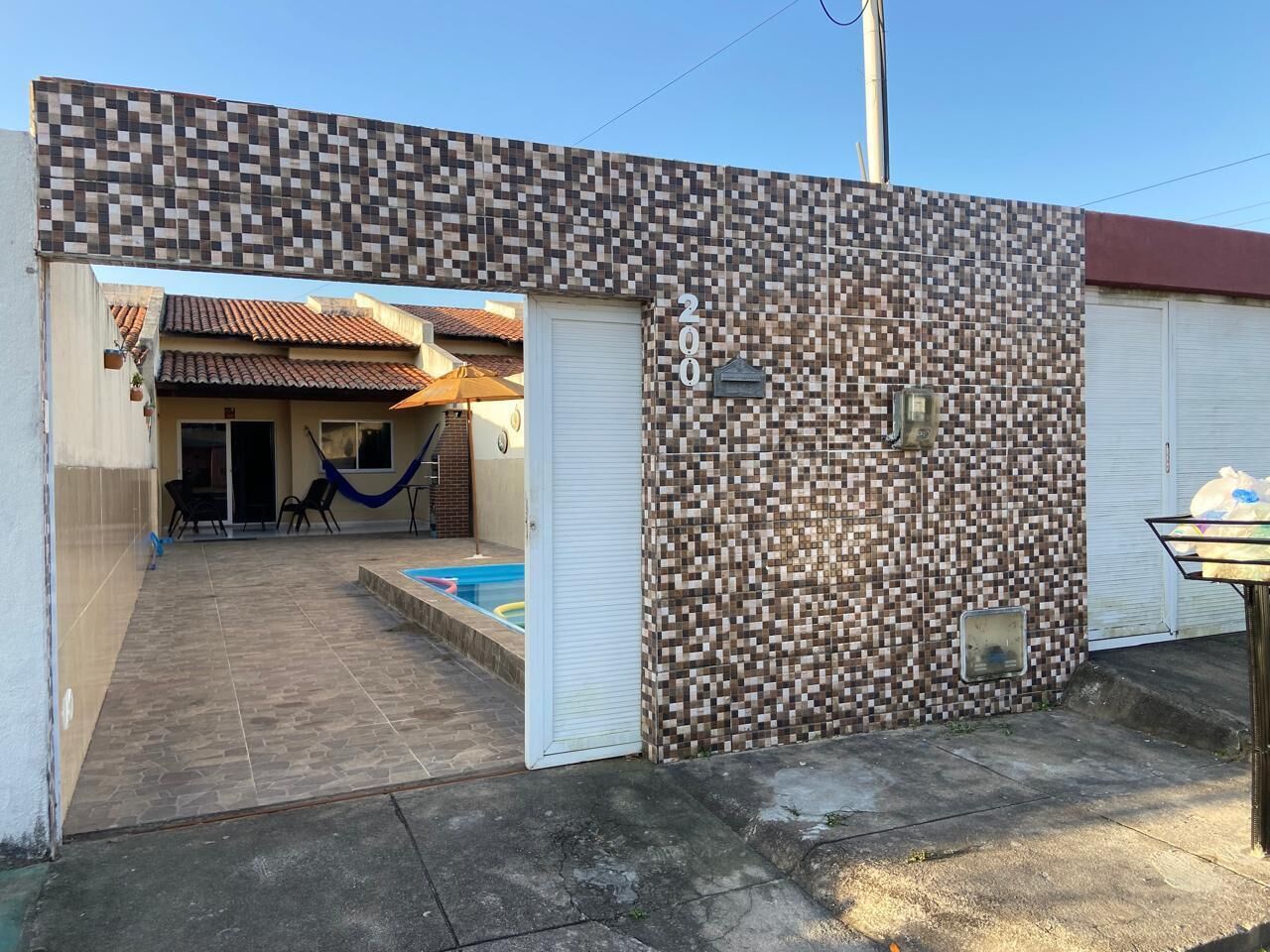 Un immeuble résidentiel à l’extérieur recouvert de carreaux, doté d’une piscine et d’un patio couvert.