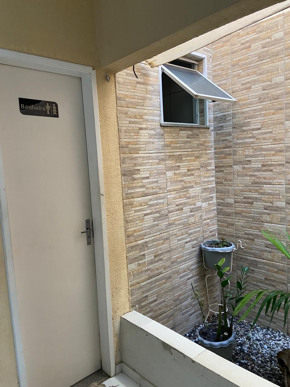 A bathroom with a tiled wall, a door labeled 'Banheiro,' and a small window.