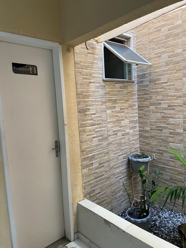 A bathroom with a tiled wall, a door labeled 'Banheiro,' and a small window.