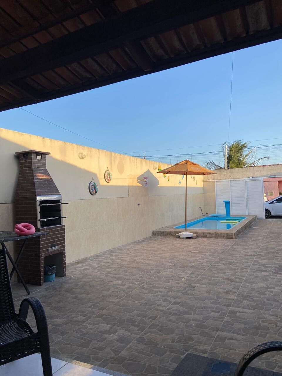Un patio couvert comprenant un barbecue, une petite piscine et une table avec des chaises.