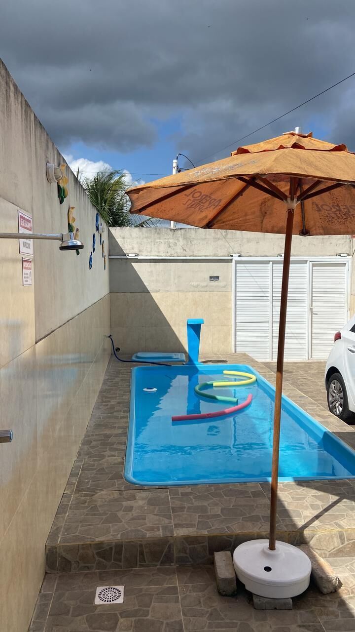 Ein Schwimmbecken mit einer blauen Wasserspaltung, einem hölzernen Sonnenschirm und einem weißen Auto in der Nähe.