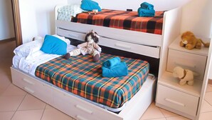 Una cama doble con una colcha escocesa, un pequeño coche de juguete, un peluche y una toalla doblada.