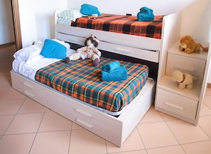 A double bed with a plaid bedspread, a small toy car, a plush toy, and a folded towel. - Villa with a garden in the heart of Monferrato (Piemonte)