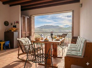 A balcony with a table set for dining, chairs, and a sofa. - Villa with a garden in the heart of Monferrato (Piemonte)