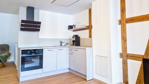 Une cuisine moderne avec des meubles blancs, un four encastré, un lave-vaisselle et une machine à café.