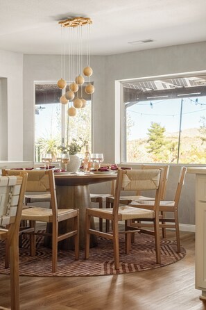 Un coin repas avec une table ronde, des chaises en bois et un luminaire suspendu.