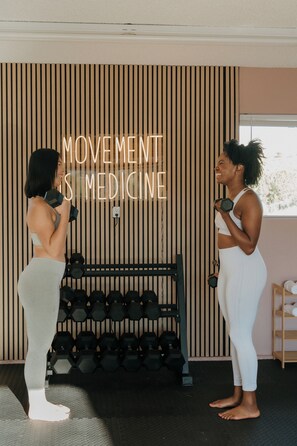 Two individuals exercising with dumbbells in a room with a wooden slat wall and a rack of dumbbells. - Desert Dreams: private pool, sauna, cold plunge, star dome, gym and theatre (Yucca Valley)