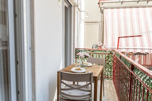 A balcony with a table and chair, a red railing, and a patterned wall. - [Luxury Suite] Ponente Apartment (Giovinazzo(BA))