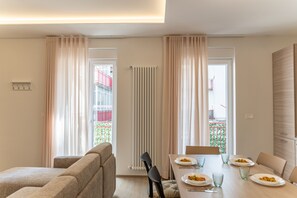 A dining area with a table set for two, a sofa, and a radiator. - [Luxury Suite] Ponente Apartment (Giovinazzo(BA))