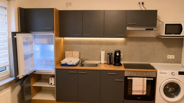 A compact kitchen with a built-in washing machine, a microwave, and a coffee maker. - Modern Vacation Rental in Idar-Oberstein (Algenrodt) (Idar-Oberstein)