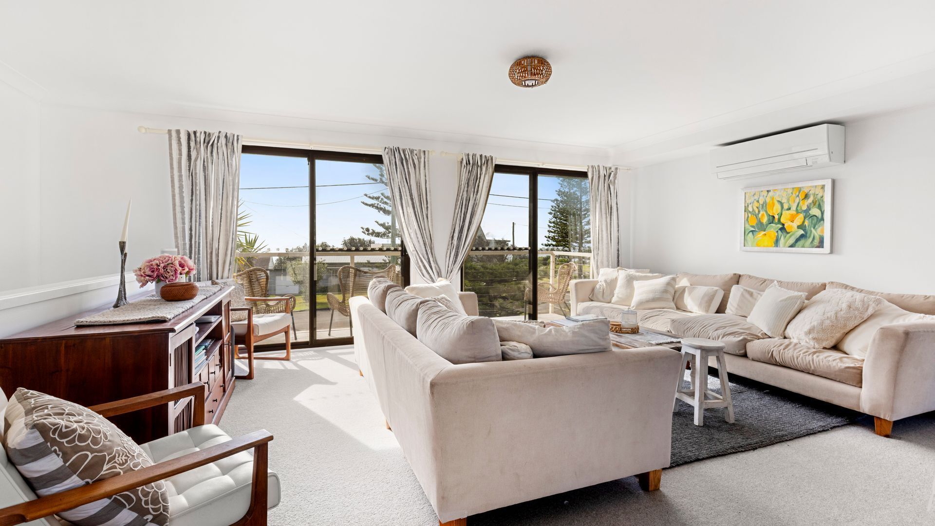 A spacious living room with a large sofa set, a coffee table, and a dining area with chairs.