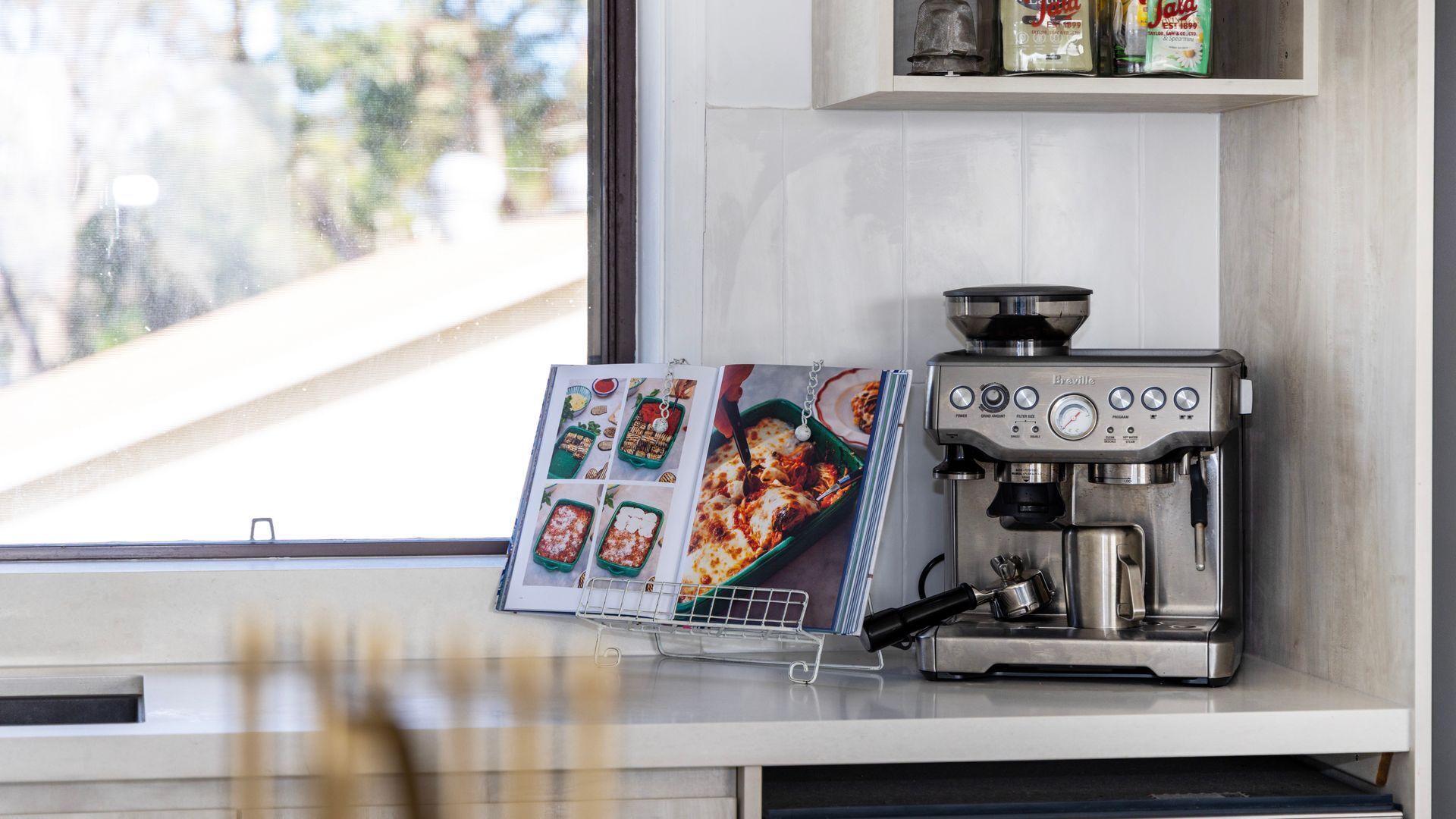 A kitchen with a coffee machine and a cookbook on the counter.