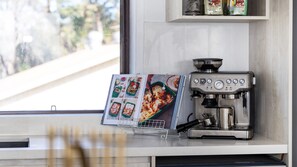 A kitchen with a coffee machine and a cookbook on the counter. - The Beach Bach - Pet Friendly with Firepit (Culburra Beach)