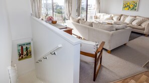 A staircase leading to a living area with a sofa and a painting on the wall. - The Beach Bach - Pet Friendly with Firepit (Culburra Beach)
