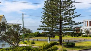 A residential area with a large pine tree, a road, and a view of the sea. - The Beach Bach - Pet Friendly with Firepit (Culburra Beach)