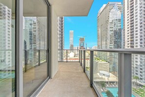 Ein Balkon mit freiem Blick auf umliegende Hochhäuser und ein weit entferntes Schwimmbad.
