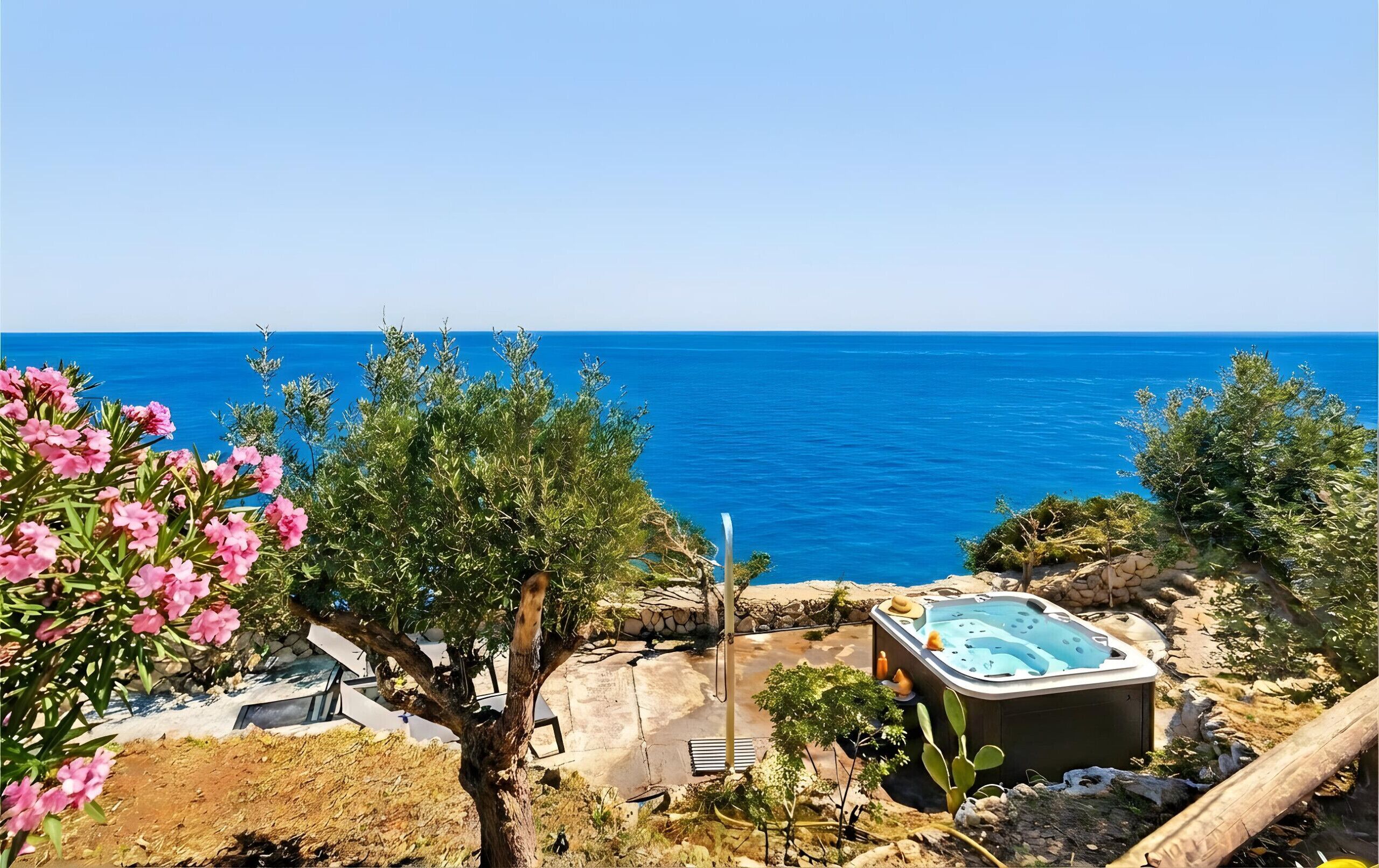 Tinaco con vistas al mar, rodeado de vegetación y un muro de piedra.