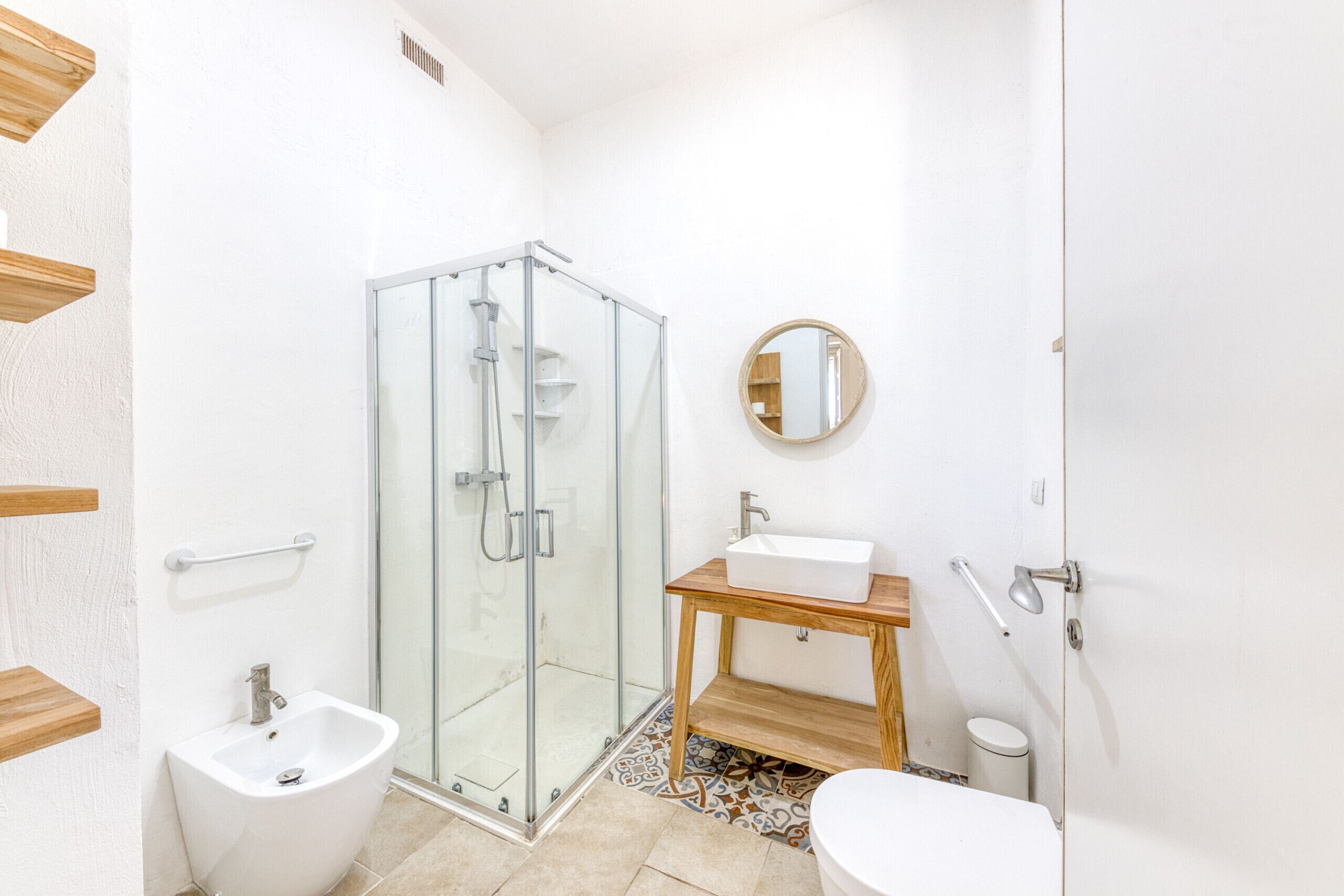 Ein Badezimmer mit Duschkabine aus Glas, einem Holzkosmetikschrank mit Waschbecken und einem Bidet.