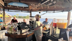 En bar med skranke, barudstyr og udsigt til stranden.