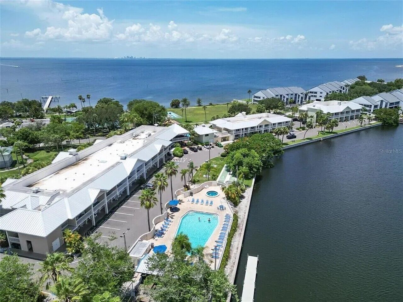 A resort with a swimming pool, waterfront view, and modern buildings.