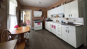Uma cozinha compacta com armários brancos, uma mesa de jantar e um micro-ondas.