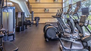 Ein Fitnessstudio mit Cardiogeräten, Krafttrainingsgeräten und einer Treppe.