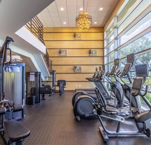 Ein Fitnessstudio mit Cardiogeräten, Krafttrainingsgeräten und einer Treppe.