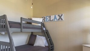Ein Stockbett mit einer Leiter, ein kleiner Nachttisch und ein an der Wand befestigtes Schild mit der Aufschrift 'RELAX'.