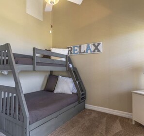 Ein Stockbett mit einer Leiter, ein kleiner Nachttisch und ein an der Wand befestigtes Schild mit der Aufschrift 'RELAX'.