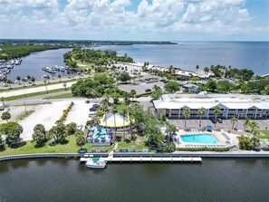 Eine Vogelperspektive zeigt ein Hotel mit Schwimmbad, einer Marina und einem großen Gebäude mit flachem Dach.