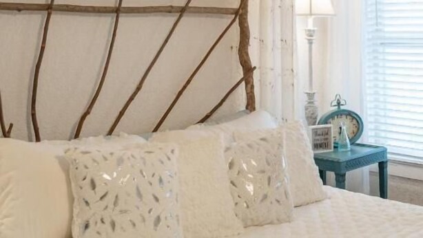 A bed with a wooden headboard, white bedding, and decorative pillows. - Sunday Morning at Savannahs (New Windsor)