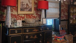 A room with a black cabinet with ornate carvings, two red lamps, a chandelier, and a patterned wall. - Sunday Morning at Savannahs (New Windsor)