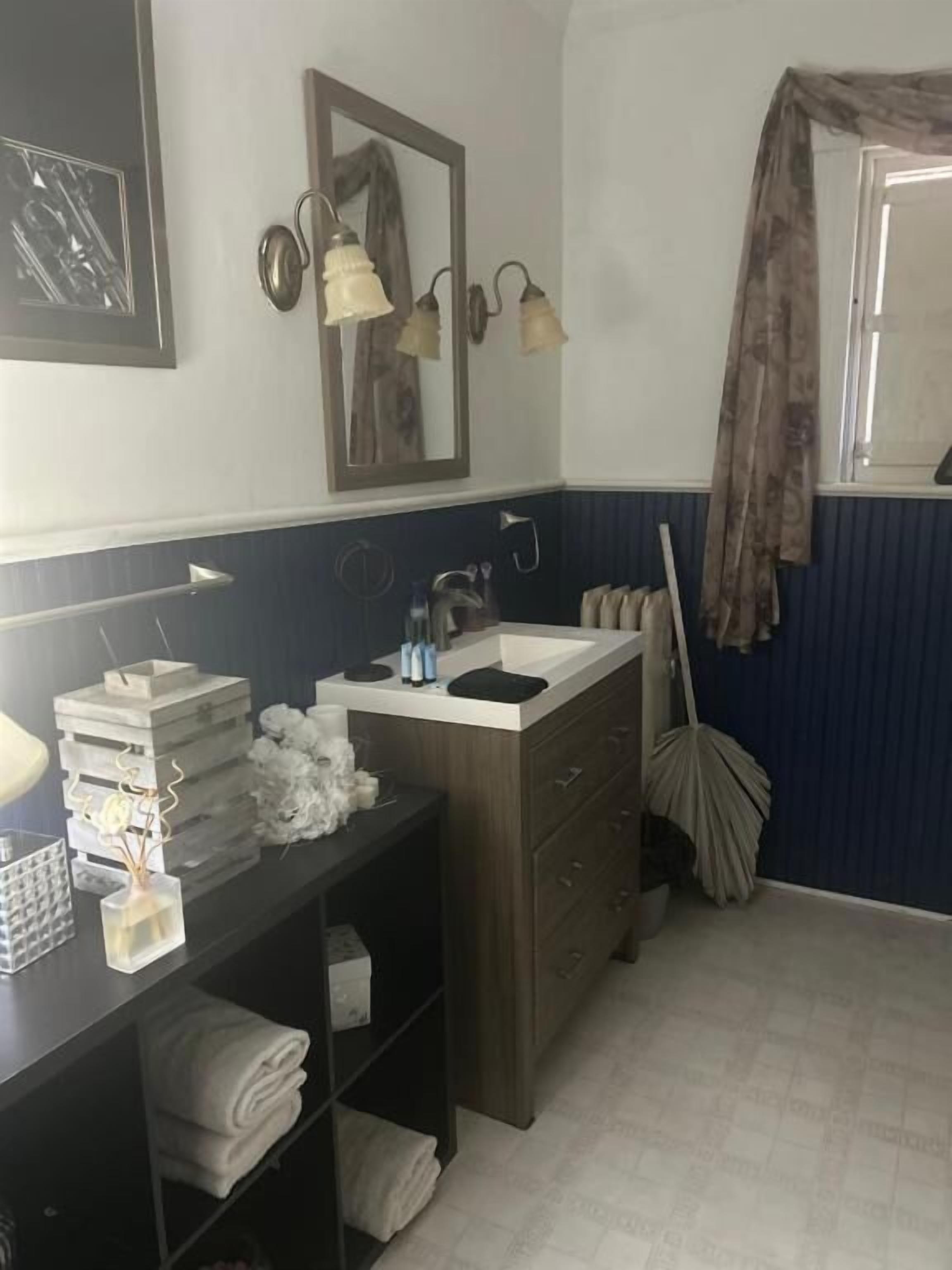 A bathroom with a sink, mirror, towel rack, and a mop.