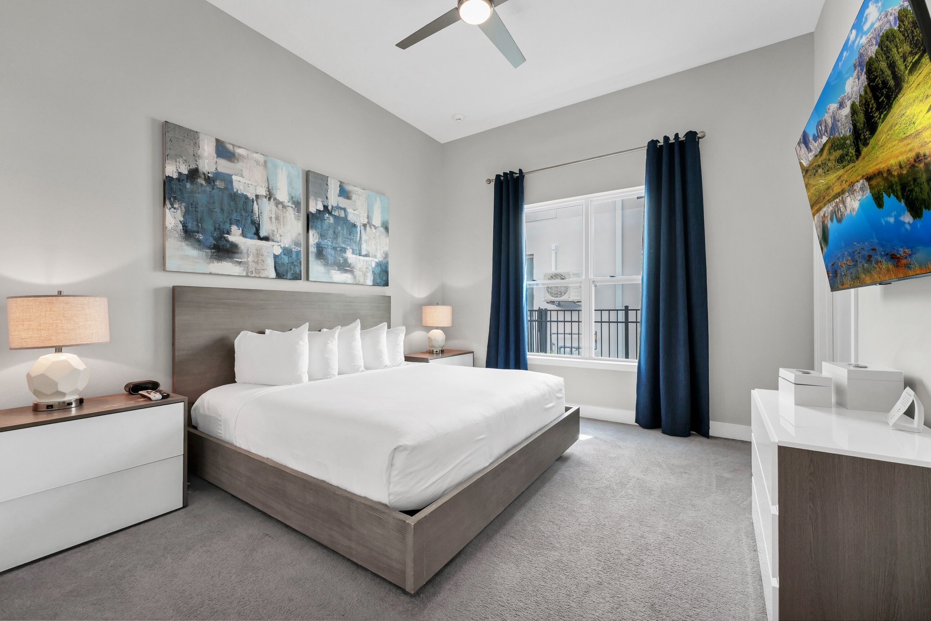 Ein modernes Hotelzimmer mit einem großen Bett, zwei Nachttischen, einem Schreibtisch und einem Deckenventilator.