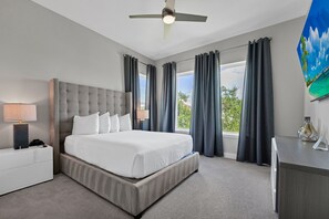 A hotel room with a large bed, a desk, a ceiling fan, and a window with curtains. - Elegant Home near Disney with Resort & Waterpark Access - 1002JN (Kissimmee)