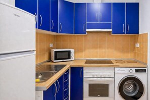 A compact kitchen with a microwave, sink, stove, and washing machine. - GuestReady - Rosamar M Apartments (Las Palmas de Gran Canaria)