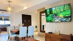 A modern living room with a flat-screen TV, dining area, and a large mirror. - Cancun Bella & Vista Apartment Deluxe (Cancun)