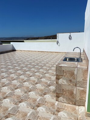 A rooftop patio with a stone-tiled floor, a built-in sink, and a view of the landscape. - Casa Adriana. Comfort and safety. (El Sauzal)